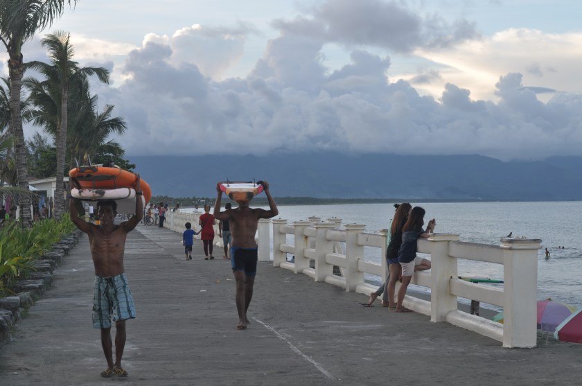 AFTER ANOTHER DAY, local surfers go home carrying surf boards on their head.