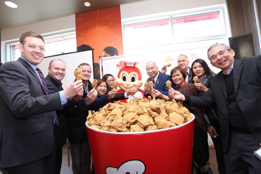 Jollibee executives and special guests gather around a giant bucket of fried chicken for the Jolly Crispy Chicken toast. Seen here are JFC Group President for North America and Foreign Franchise Brands Jose Miñana, VP and General Manager of Jollibee North America Maribeth dela Cruz, Honorary Consul Ronald Opina, Member of the Legislative Assembly for St. Norbert Jon Reyes, President of Sysco Winnipeg Blair Schmidt, Trevor Skinner, and other special guests.